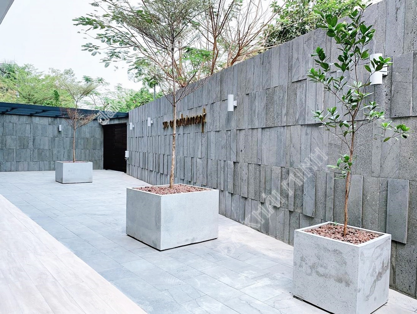Tường ốp đá ong xám tại sân cảnh quan của khu du lịch